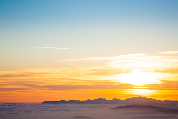 イタリアアルプスからの日没時の山のシルエット。雲の背景