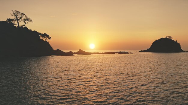 Mountain silhouette at sunset seascape aerial Rocks of tropic island at ocean bay Summer paradise