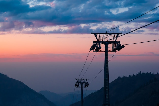 美しいカラフルな夕日の背景に山のスキーリフト。