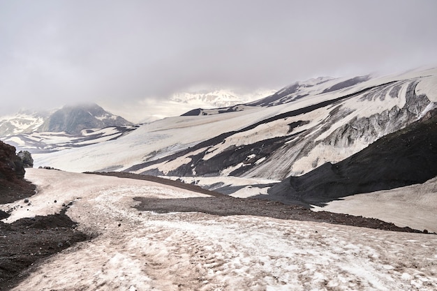 Pendii di montagna e roccia vulcanica nera ricoperta di neve.