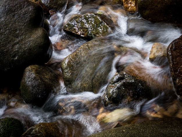 Mountain stream creek waterfall flowing through rocks in a tropical forest.