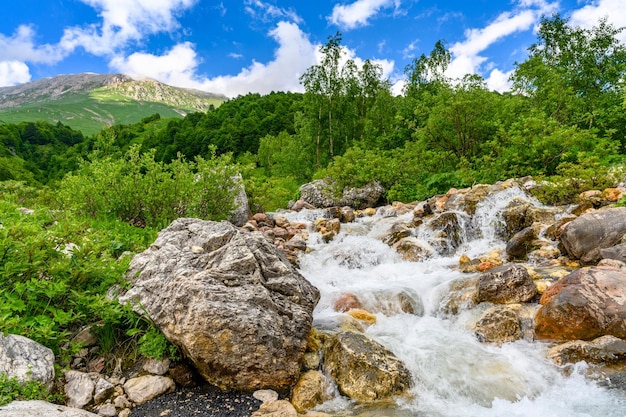 高山の山々に滝のある渓流、山の緑のある美しい風景
