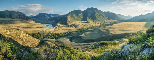 対照的な夕方の光の山の谷のパノラマ