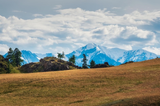 Вид на горы с небом, облаками и красной травой. Яркие пейзажи остроконечных гор и осенних кедровых лесов в Алтайском крае, Сибирь.
