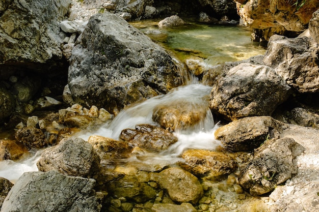 Mountain waterfall with sunlit boulders and lush greenery serene and captivating