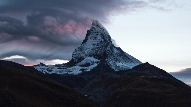 a mountain with a pink cloud in the sky above it