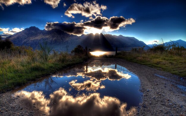 a mountain with a reflection of the sun and clouds in the water