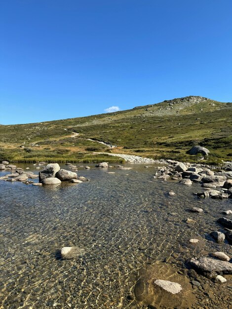 a mountain with a stream running through it and a mountain in the background