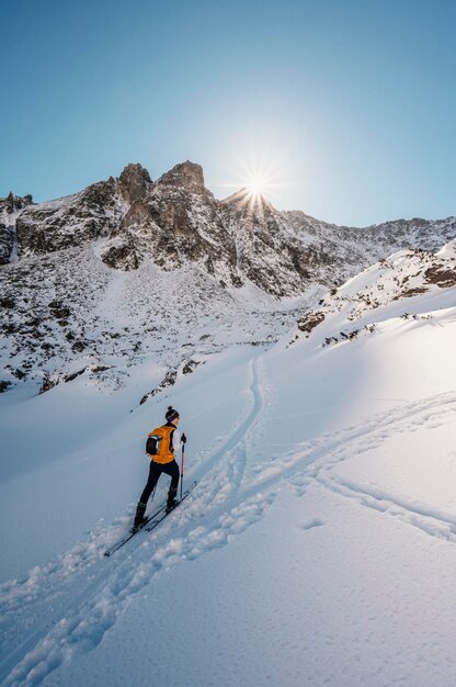 Mountaineer backcountry ski walking ski alpinist in the mountains Ski touring in alpine landscape with snowy trees Adventure winter sport