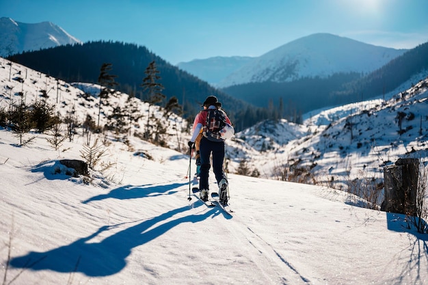 Mountaineer backcountry ski walking ski alpinist in the mountains Ski touring in alpine landscape with snowy trees Adventure winter sport