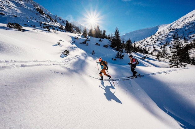 Mountaineer backcountry ski walking ski alpinist in the mountains Ski touring in alpine landscape with snowy trees Adventure winter sport