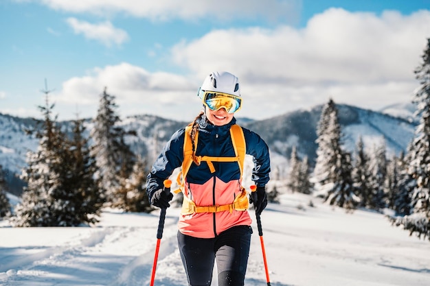 Mountaineer backcountry ski walking ski woman alpinist in the mountains Ski touring in alpine landscape with snowy trees Adventure winter sport Freeride skiing