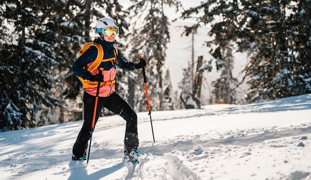 Mountaineer backcountry ski walking ski woman alpinist in the mountains Ski touring in alpine landscape with snowy trees Adventure winter sport Freeride skiing