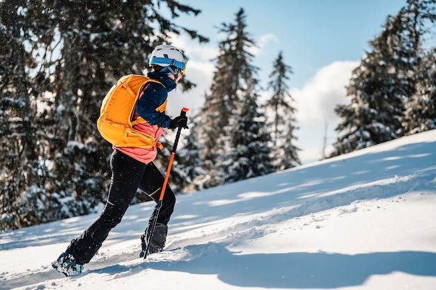 Mountaineer backcountry ski walking ski woman alpinist in the mountains Ski touring in alpine landscape with snowy trees Adventure winter sport Freeride skiing