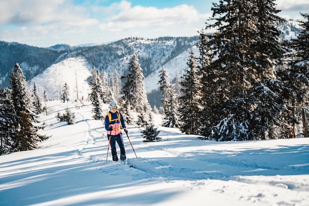산악인 오지 스키 워킹 스키 여성 산 속의 산악인 눈 덮인 나무가 있는 고산 풍경에서 스키 투어 겨울 스포츠 모험 겨울 스포츠 프리라이드 스키