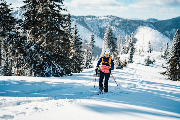 산악인 오지 스키 워킹 스키 여성 산 속의 산악인 눈 덮인 나무가 있는 고산 풍경에서 스키 투어 겨울 스포츠 모험 겨울 스포츠 프리라이드 스키
