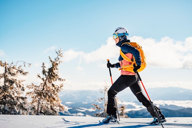 Mountaineer backcountry ski walking ski woman alpinist in the mountains Ski touring in alpine landscape with snowy trees Adventure winter sport Freeride skiing