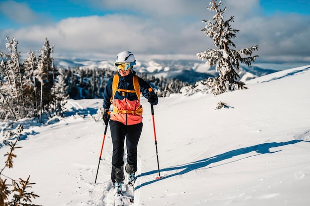 Mountaineer backcountry ski walking ski woman alpinist in the mountains Ski touring in alpine landscape with snowy trees Adventure winter sport Freeride skiing