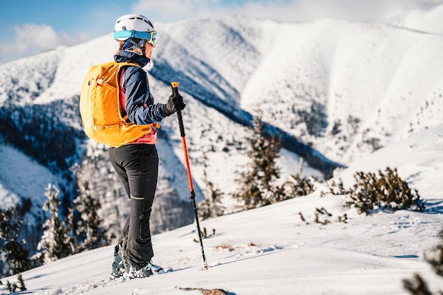 Mountaineer backcountry ski walking ski woman alpinist in the mountains Ski touring in alpine landscape with snowy trees Adventure winter sport Freeride skiing