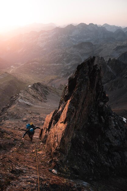 Photo mountaineer climbs among sharp rocks illuminated by the sunrise in an alpine adventure in the pyrenees