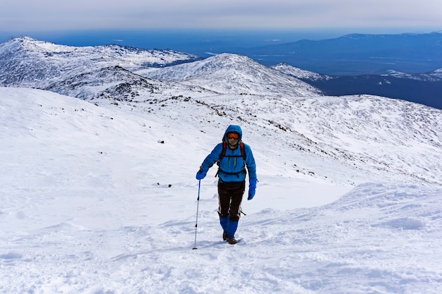 登山家は雪に覆われた山の斜面を登ります