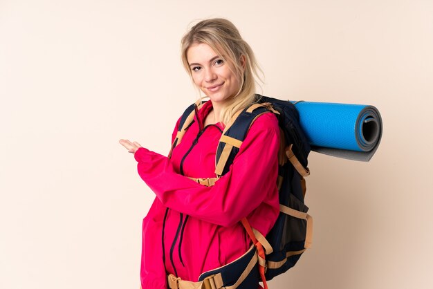 Mountaineer woman with a big backpack over isolated wall extending hands to the side for inviting to come