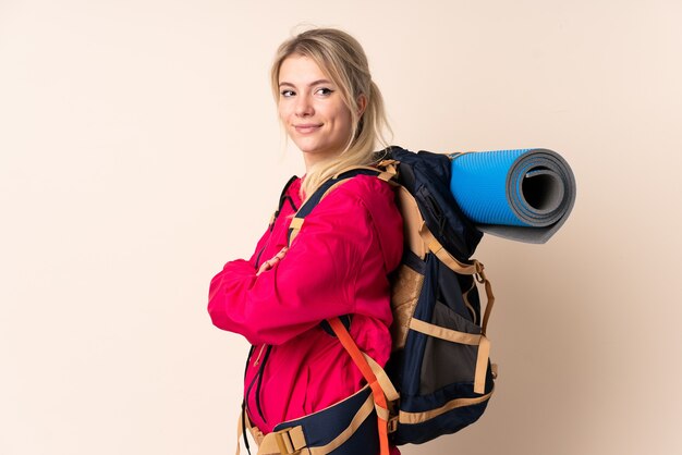 Mountaineer woman with a big backpack over isolated wall looking to the side