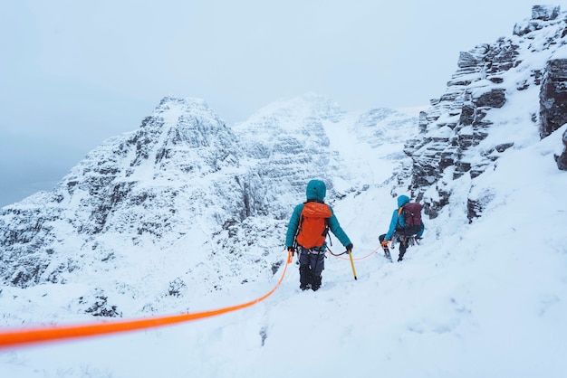 スコットランドの雪に覆われたリアサックの尾根を登る登山家