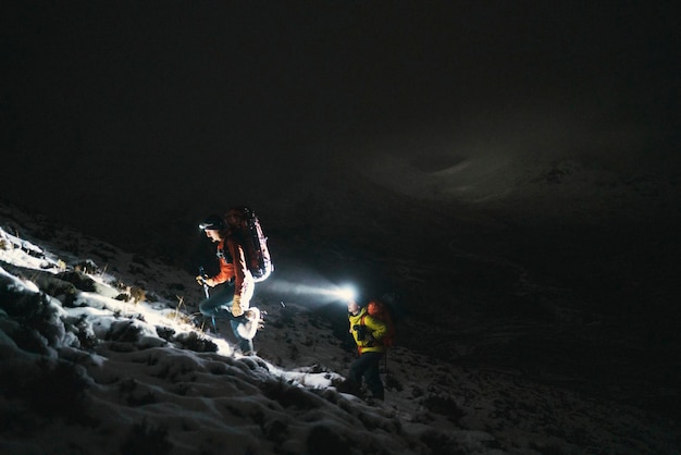 スコットランドのグレンコーで寒い夜にトレッキングする登山家