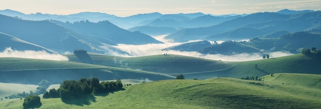 谷のパノラマビューの朝の明るい霧の山と丘