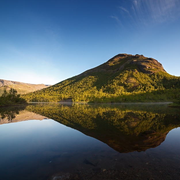 Mountains reflected in the smooth surface of the lake at dawn.