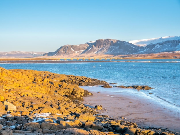 アイスランドの青い空の下で冬の山の海と海岸線の景色