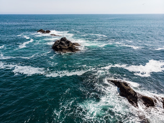 Photo mountains of which protrude from the water, the waves break on them