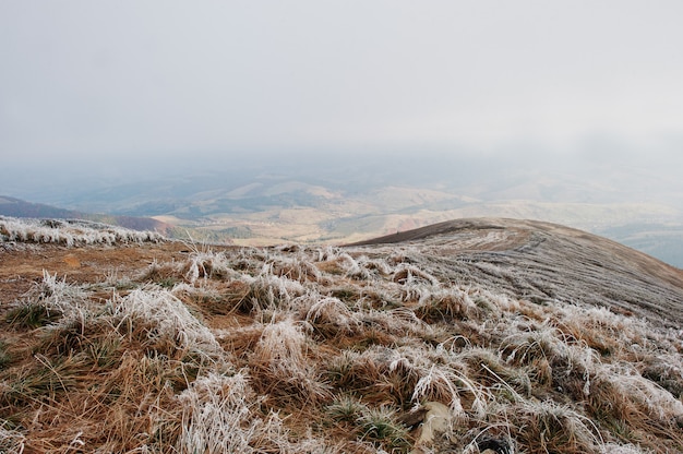 Горные склоны с замерзшей травой и туман на холме.