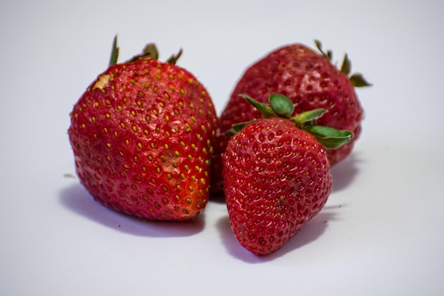 mounted strawberries in the foreground with shadows and white background