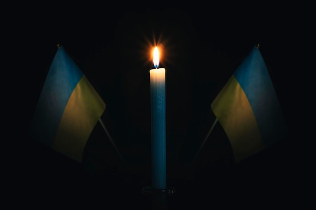 Mourning in the country burning candle on the background of the Ukraine flag Victims of cataclysm or war concept memorial day remembrance day National mourning