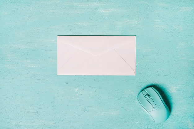 Mouse and white envelope on turquoise wooden textured background