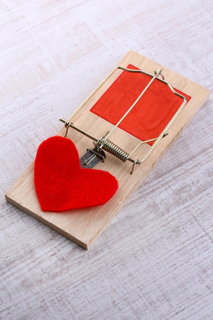 Mousetrap with heart on wooden background