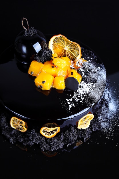 Mousse cake with black chocolate glaze with passion fruit and mango