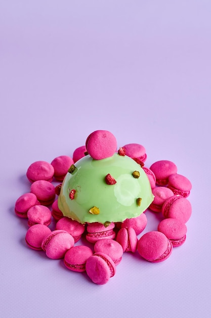 Mousse dessert on a pink background in a composition with small macaroons