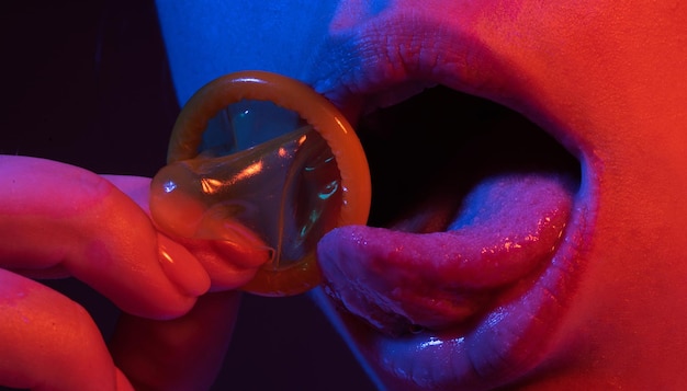 コンドームを舌でなめる女の子の口 コンドームを持ったセクシーな女性の口 コンドームを持ったセクシーな女性
