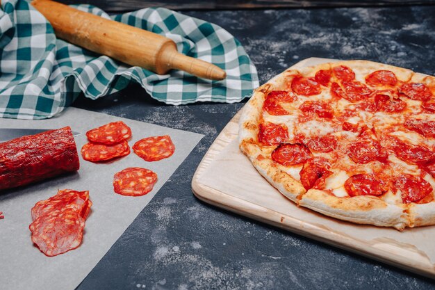 Mouth-watering neapolitan pizza on a blackboard with various ingredients, free space for text