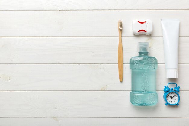 Mouthwash and other oral hygiene products on colored table top view with copy space Flat lay Dental hygiene Oral care products and space for text on light background concept