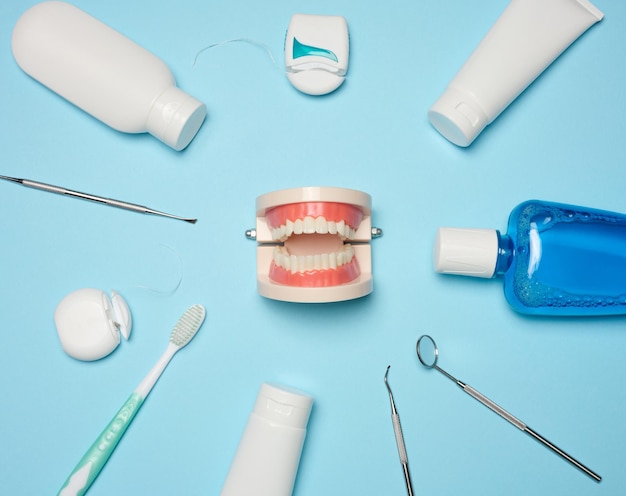 Photo mouthwash toothpaste tube dental floss and medical mirror on a blue background oral hygiene