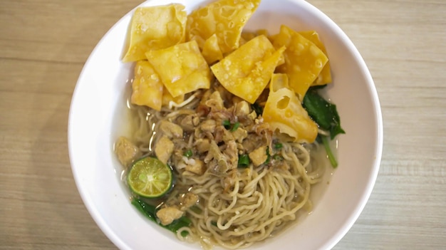 A mouthwatering bowl of Mie Ayam a popular Indonesian dish yellow wheat noodles with diced chicken mushrooms and an array of savory condiments A delightful blend of Chinese and Indonesian flavors