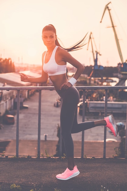 On the move. Beautiful young woman in sports clothing running along the bridge 