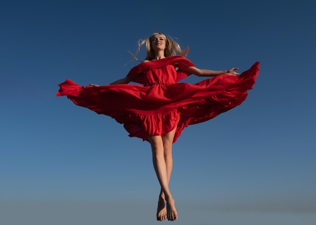 Movement girl in red dress on sky Attractive woman in fashion outfit outside Outdoor fashion photo of young beautiful lady enjoying spring