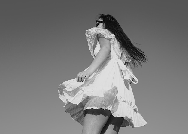 Движение девушки в белом платье на небе Модель в модном платье на открытом воздухе Беззаботные женщины на улице