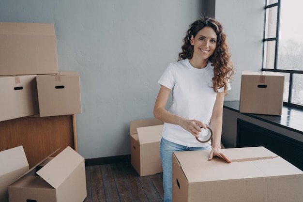 Mover is packing cargo with duct tape Young lady is wrapping cardboard boxes with packing tape