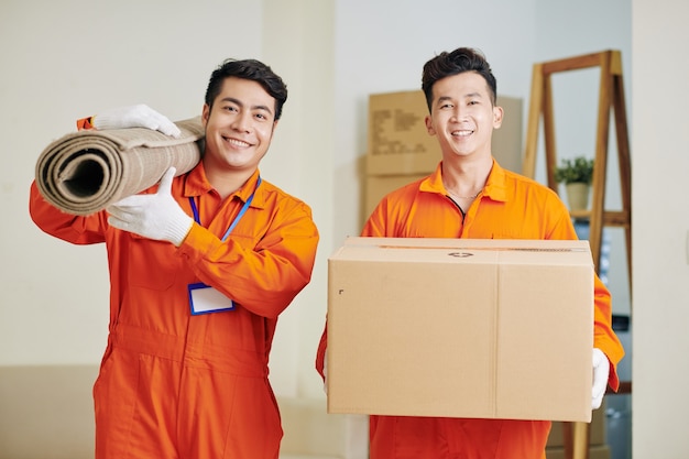 Movers carrying carpet and cardboard box